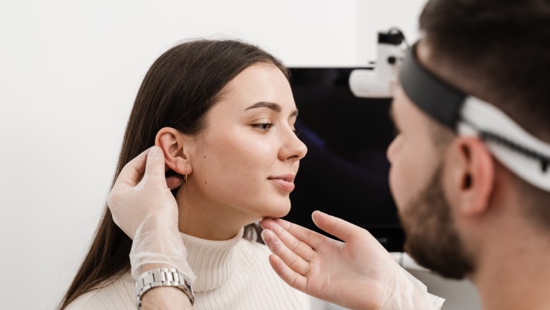 Surgeon doctor examines girl ears before otoplasty cosmetic surgery