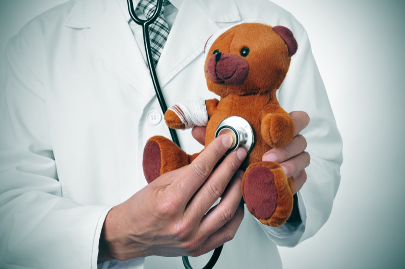 a doctor auscultating a teddy bear with bandages in its head and arm, depicting the pediatric medicine or the veterinary medicine concepts